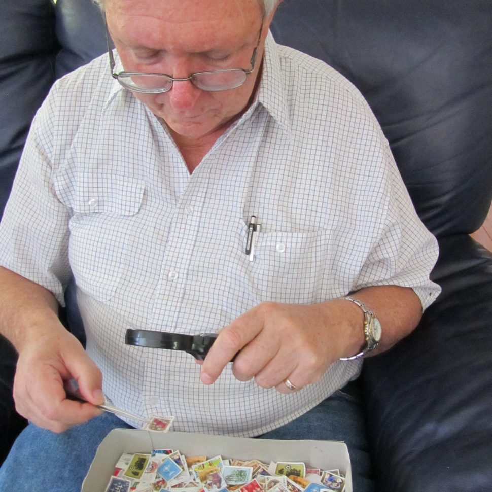 Ted Henebery sitting sorting stamps
